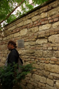 man standing next to a stone wall