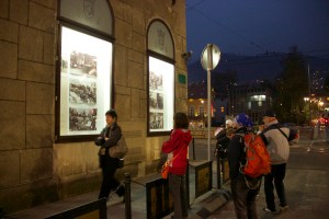 street corner at night with people looking at exhibit in windows