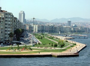 Green park space along the harbor with modern apartment buildings in the background.