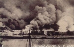 black and white photo of harbor with surrounding buildings thick with smoke