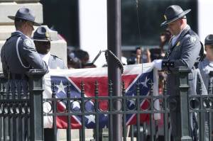 Two uniformed officers fold a Confederate battle flag.
