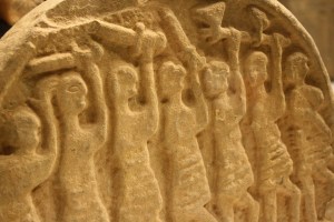 Sandstone relief showing vikings with raised weapons.