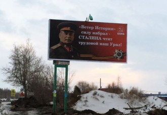 Billboard with uniformed Stalin, a slogan in Russian, and the hammer and sickle of the Communist Party.
