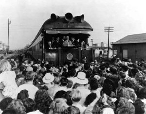 Harry Truman on back of train car speaking to crowd of people.