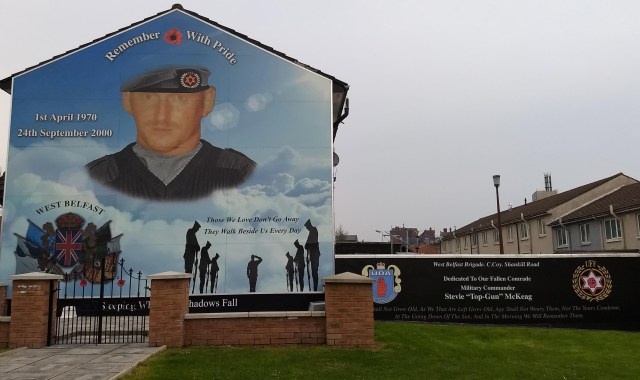 Outdoor mural captioned "Remember with Pride" and "Thoswe we Love Don't Go Away" and "Dedicated to our fallen comrade, military commander Stevie 'Top-Gun' McKeag.'"