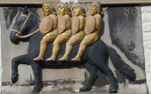 Carved image of 4 armored men on the back of a single horse.