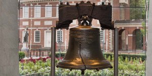 The Liberty Bell, a large metal bell with a crack through it, displayed in a garden.